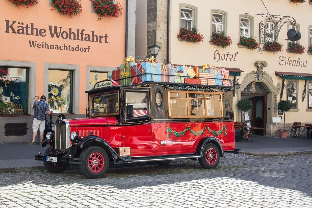 Vista da  entrada da Käthe Wohlfahrt uma das lojas mais famosas de Rothenburg ob der Tauber na Alemanha. na frente da foto está umc arro decorado de natal vermelho
