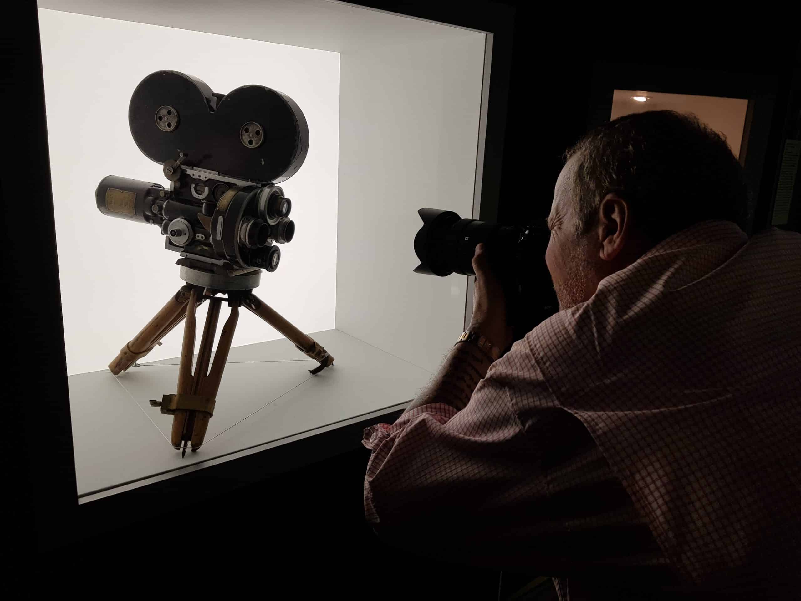 Homem registrando uma imagem de uma câmera de cinema, destacando seu interesse por filmagem.
