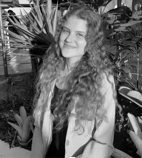 Clara-Almeida Imagem em preto e branco de uma mulher de cabelos longos e cacheados, evocando um estilo clássico e atemporal.