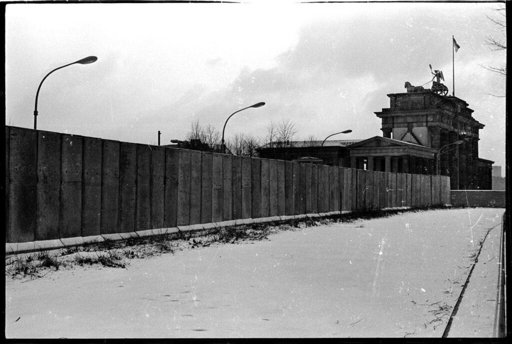 Muro de Berlín cubierto de nieve frente a la Puerta de Brandeburgo, en una foto histórica