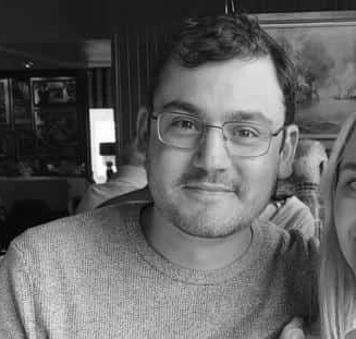 Raphael-Almeida Homem sorrindo para a câmera em um restaurante, com um ambiente acolhedor ao fundo.