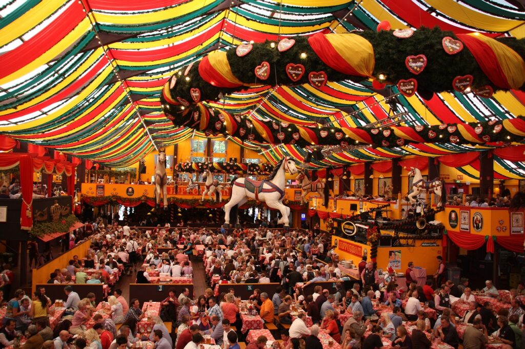 Interior de una carpa de la Oktoberfest en Múnich, llena, con decoración colorida en el techo