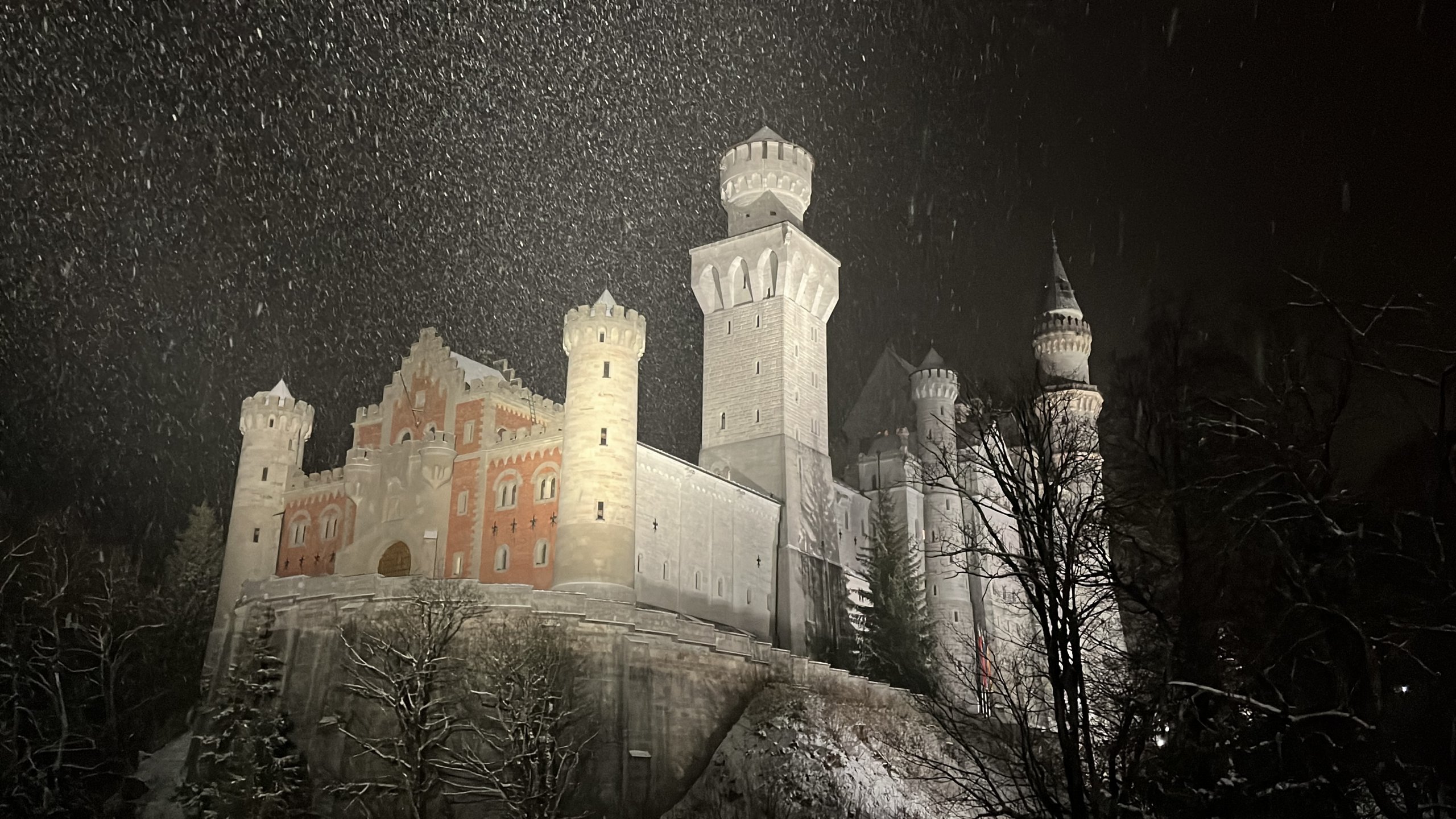 O Castelo de Neuschwanstein iluminado à noite, sob a neve, no inverno da Baviera.