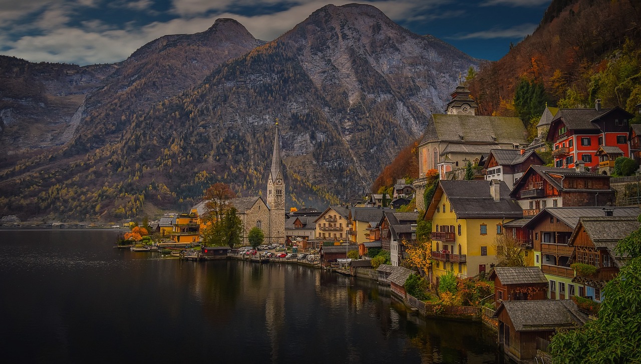 A torre da igreja de Hallstatt refletida na água parada do lago ao amanhecer, sem gente na orla