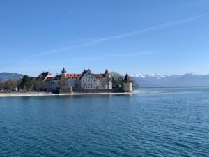 Edifícios históricos à beira do Lago de Constança, com os Alpes nevados ao fundo