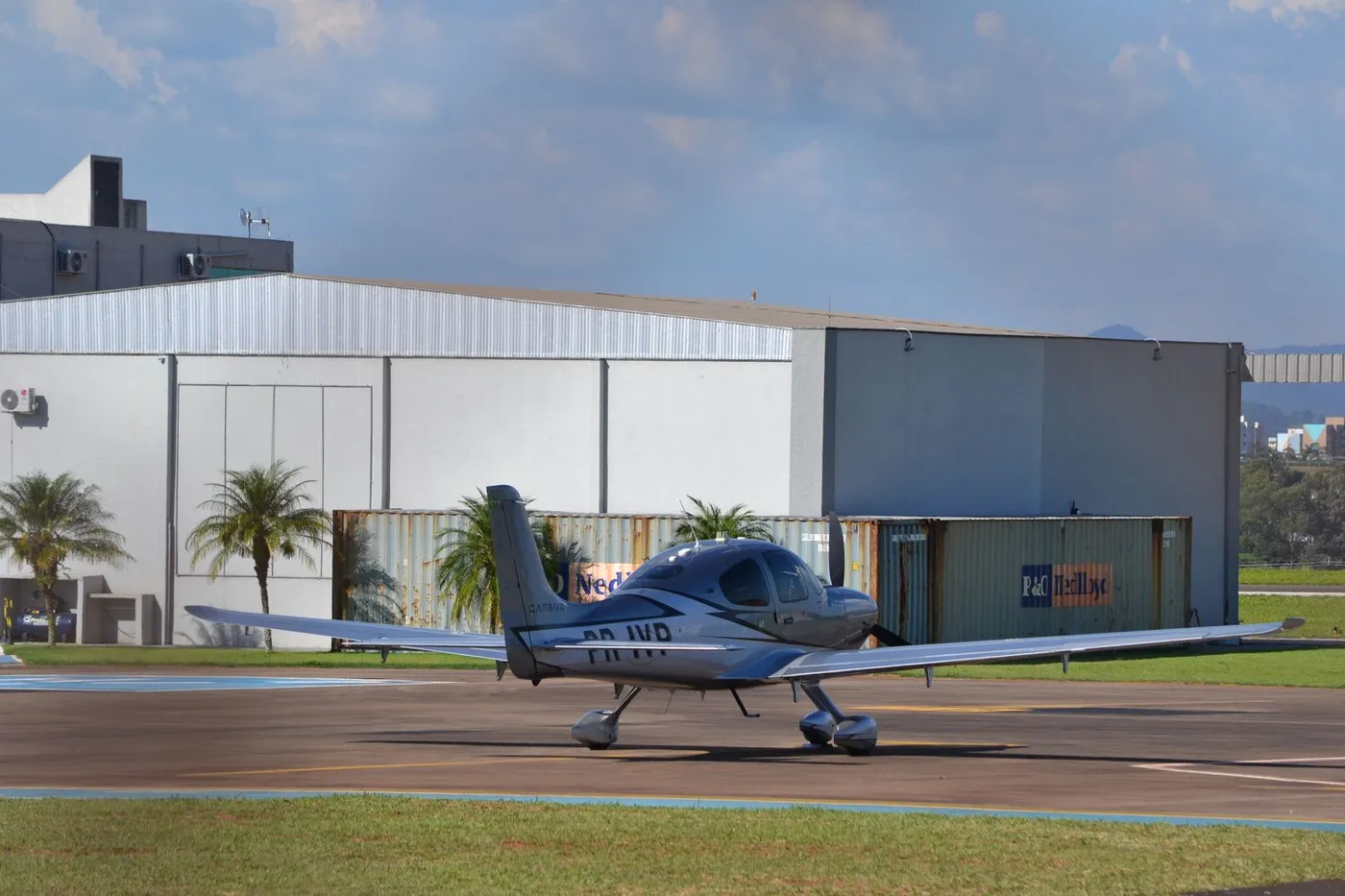 Avião leve monomotor estacionado na pista ao lado do hangar