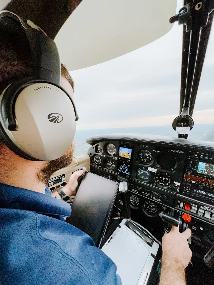 Piloto com headset aos comandos de um avião leve nos Alpes