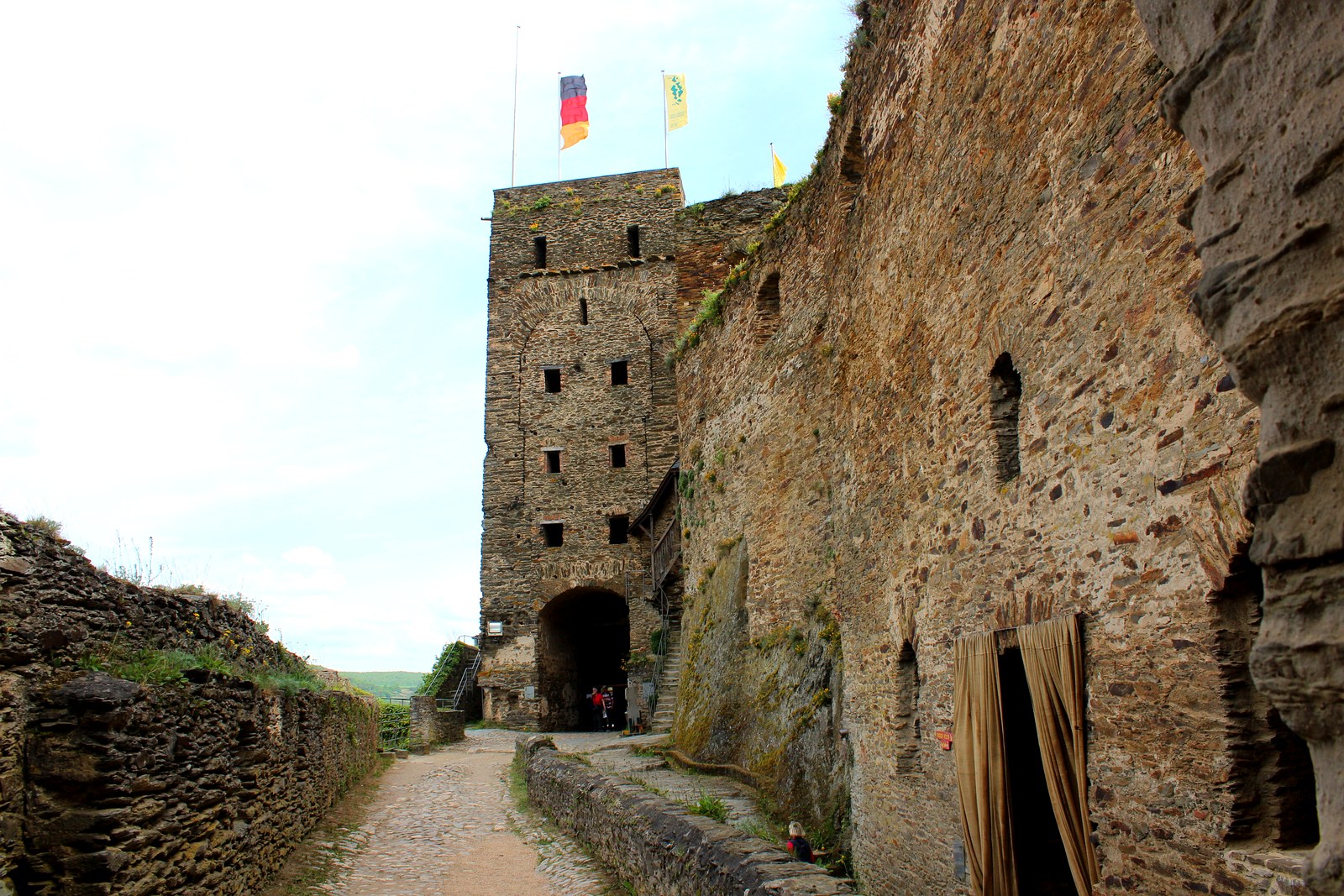 Caminho de pedra subindo até o portão sob a torre de bandeiras de Burg Rheinfels