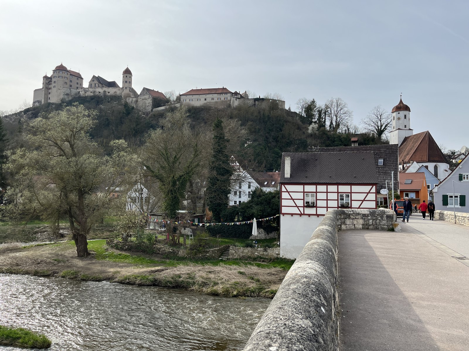 Castelo de Harburg no alto da colina visto da ponte de pedra sobre o rio Wörnitz, com casas de enxaimel à margem