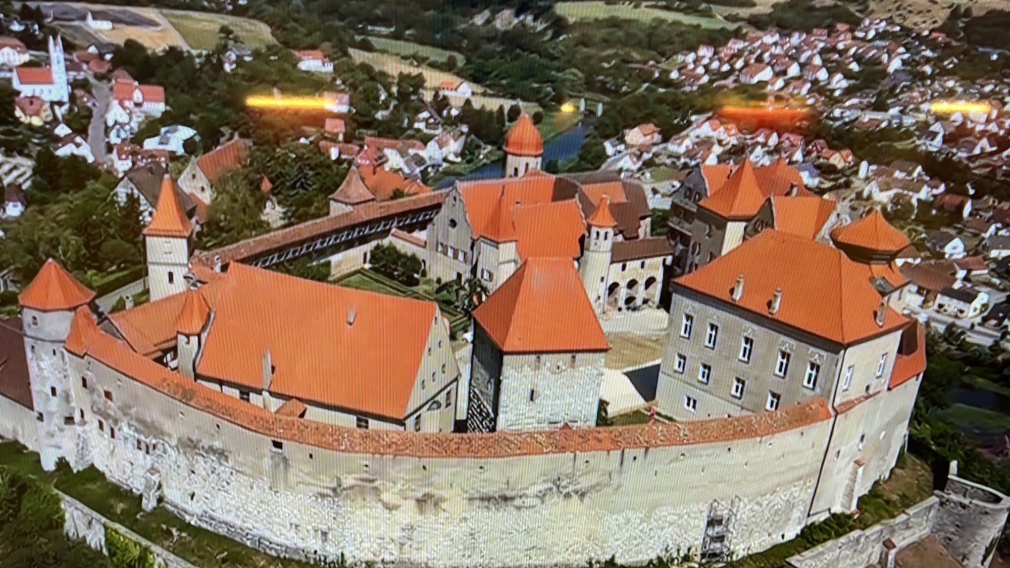 Vista aérea do Castelo de Harburg iluminado no entardecer, com os telhados vermelhos e o vilarejo ao fundo