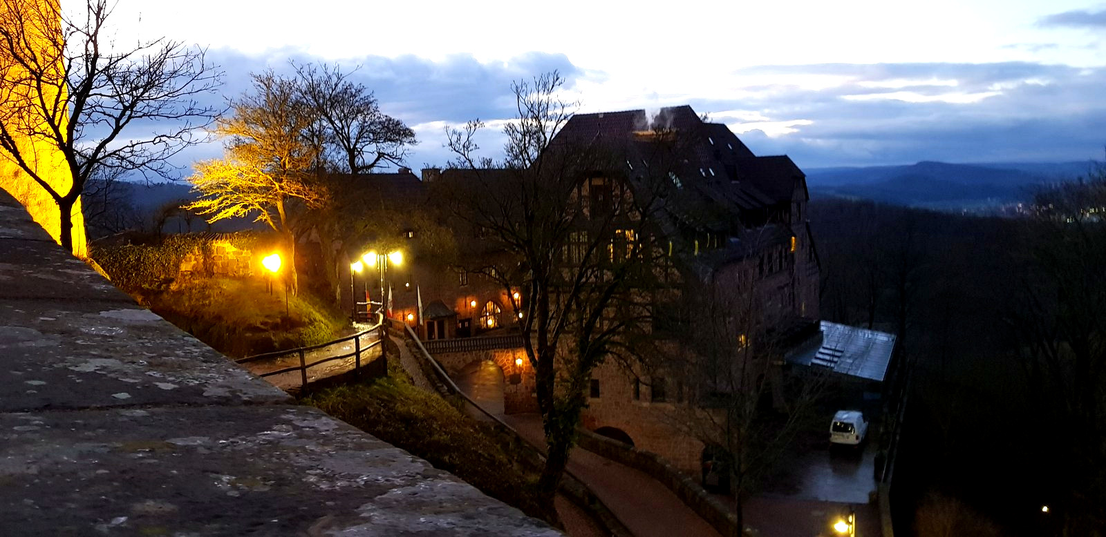 Complexo do Castelo de Wartburg iluminado ao anoitecer com o vale da Turíngia ao fundo