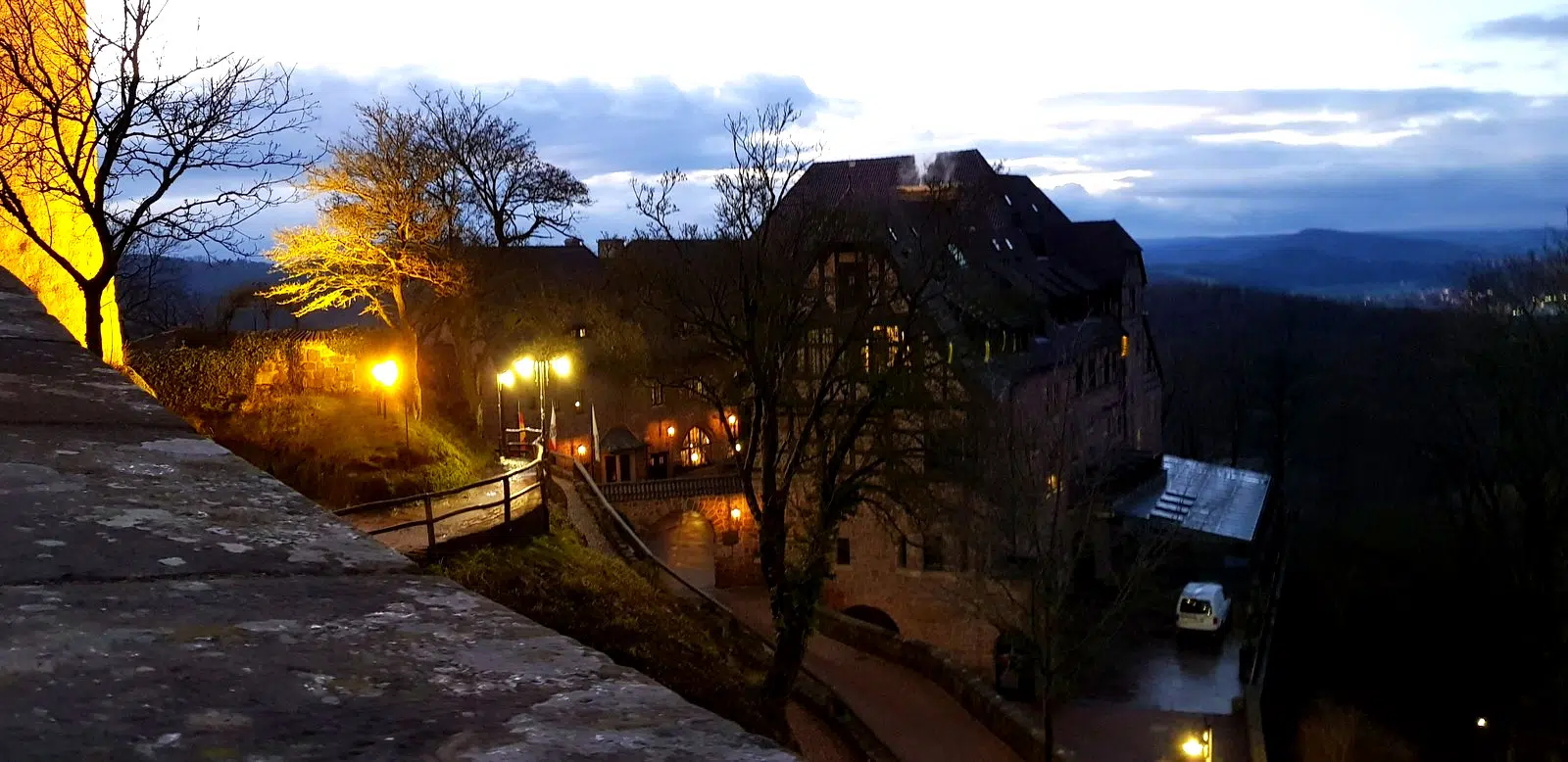 Complexo do Castelo de Wartburg iluminado ao anoitecer com o vale da Turíngia ao fundo
