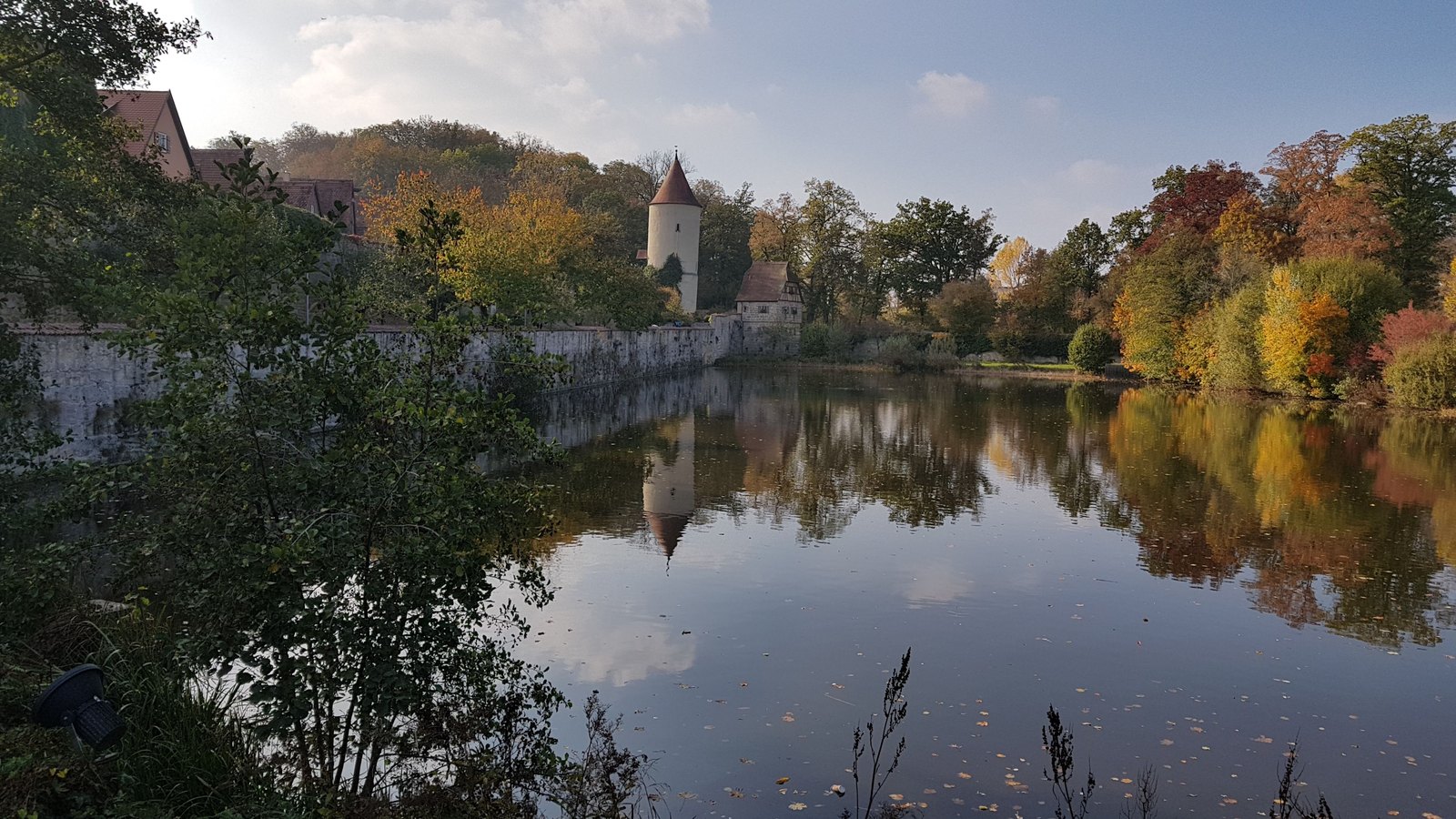 Lago do fosso de Dinkelsbühl refletindo a muralha e uma torre redonda no outono