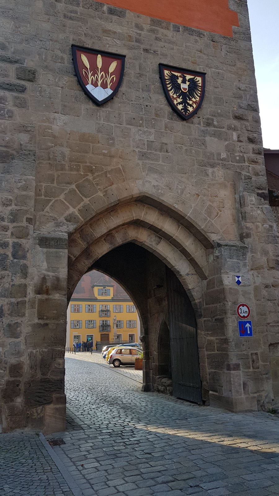 Arco gótico de portão em Dinkelsbühl com dois brasões pintados na pedra