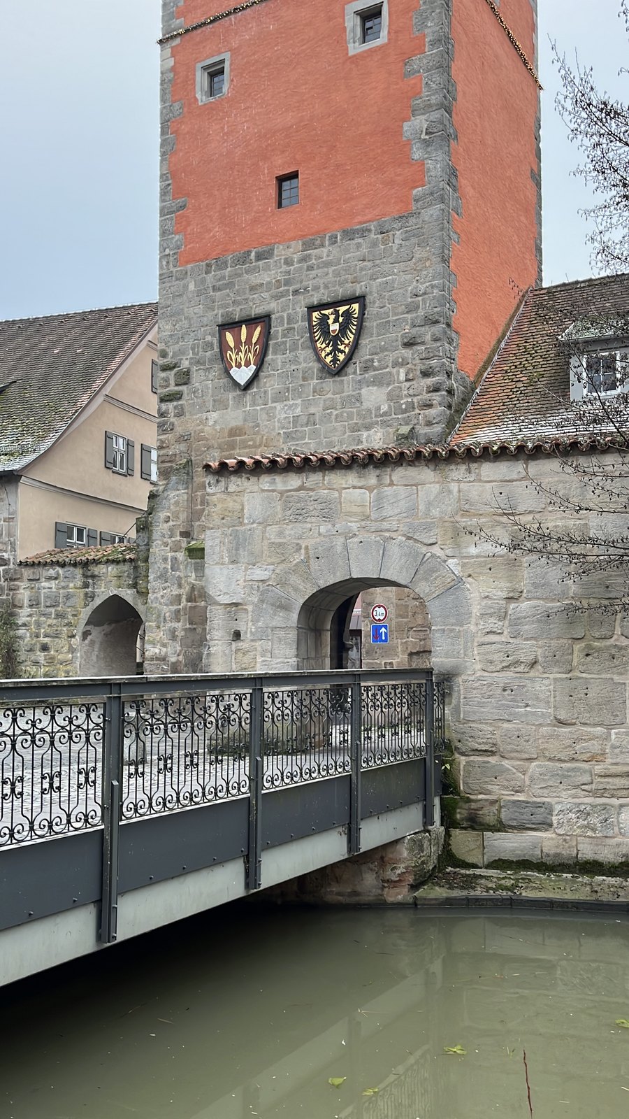Torre da muralha de Dinkelsbühl com brasões e ponte sobre o fosso no inverno