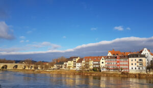 Casario colorido à beira do Danúbio em Regensburg com os arcos da Ponte de Pedra à esquerda
