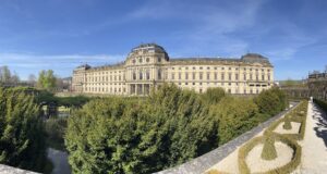 Residência de Würzburg vista do Hofgarten, com a fachada barroca ao fundo e as sebes e canteiros do jardim em primeiro plano