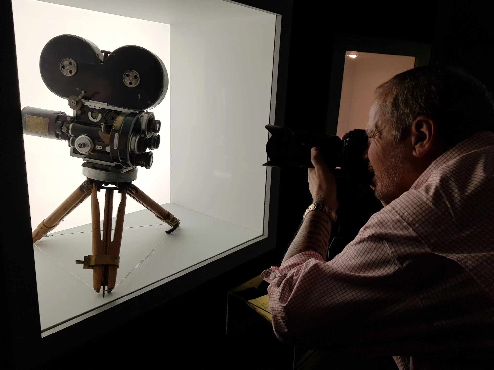 Visitante fotografando uma câmera de cinema exposta em uma vitrine