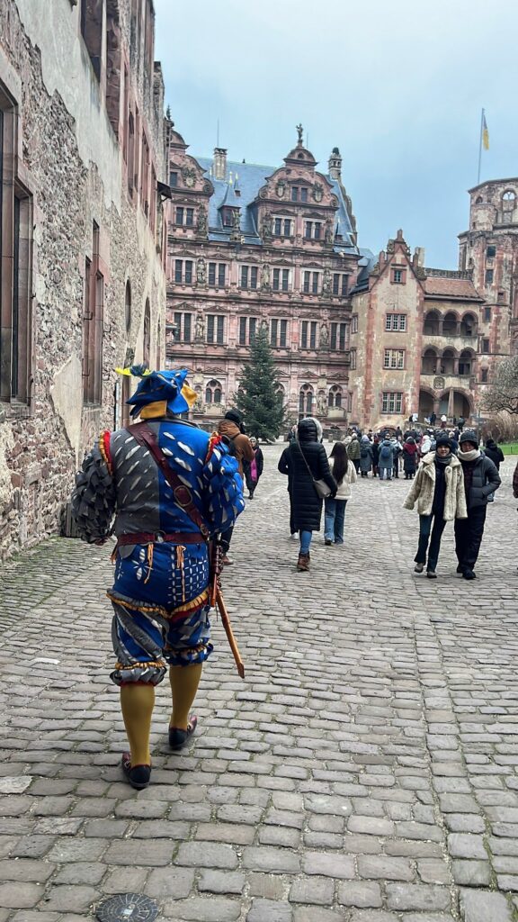 Guia com traje de época azul e amarelo caminhando em direção ao Friedrichsbau