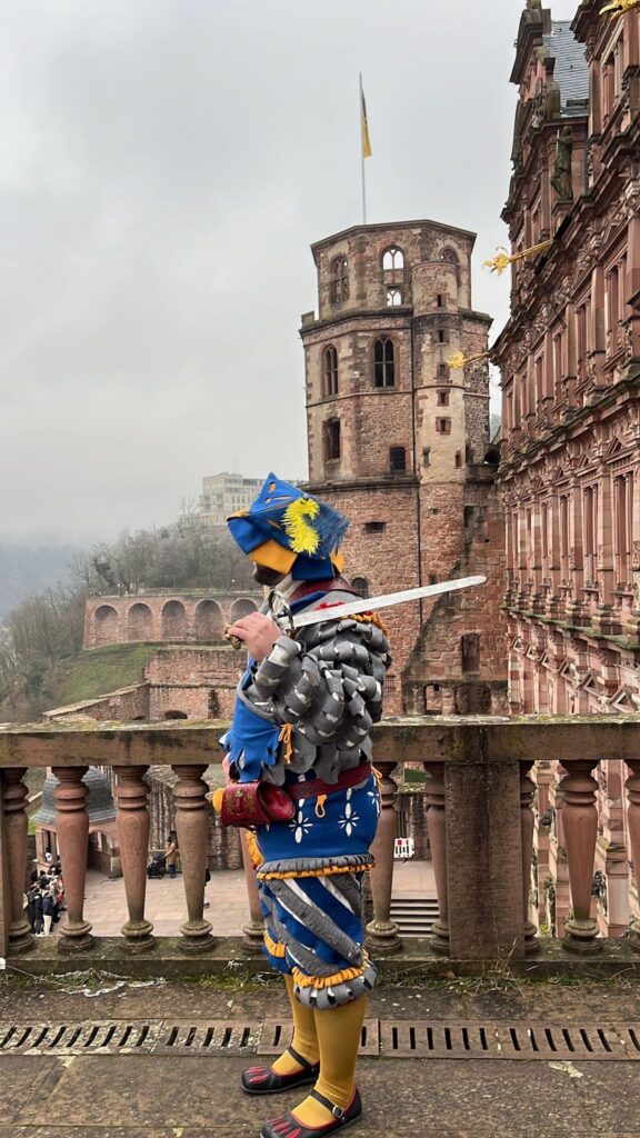 Guia com traje de época azul e amarelo em um terraço do castelo no inverno