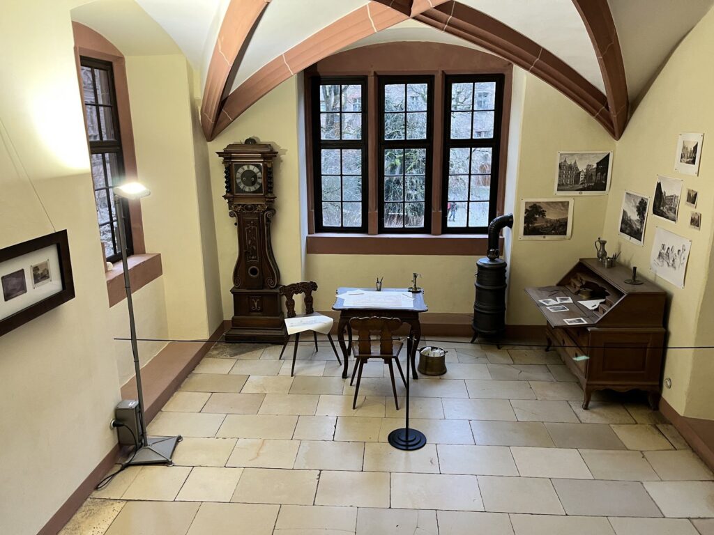 Sala mobiliada com relógio de pé e escrivaninha no interior do Castelo de Heidelberg