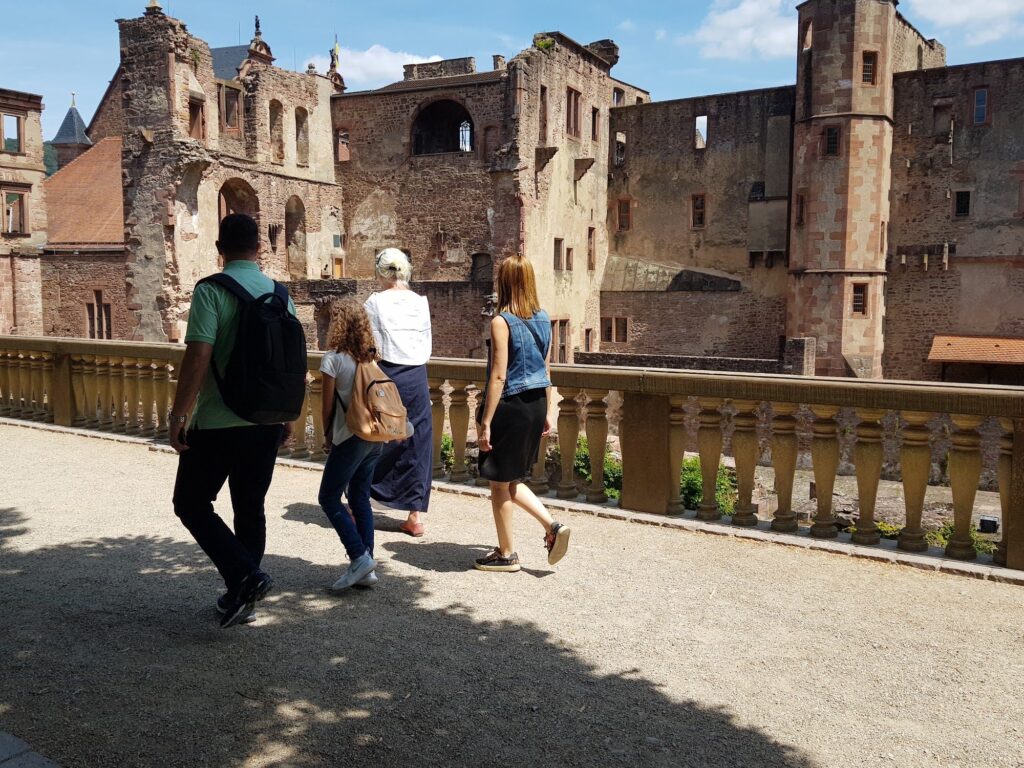 Viajantes caminhando pelo terraço com balaustrada acima das ruínas do Castelo de Heidelberg
