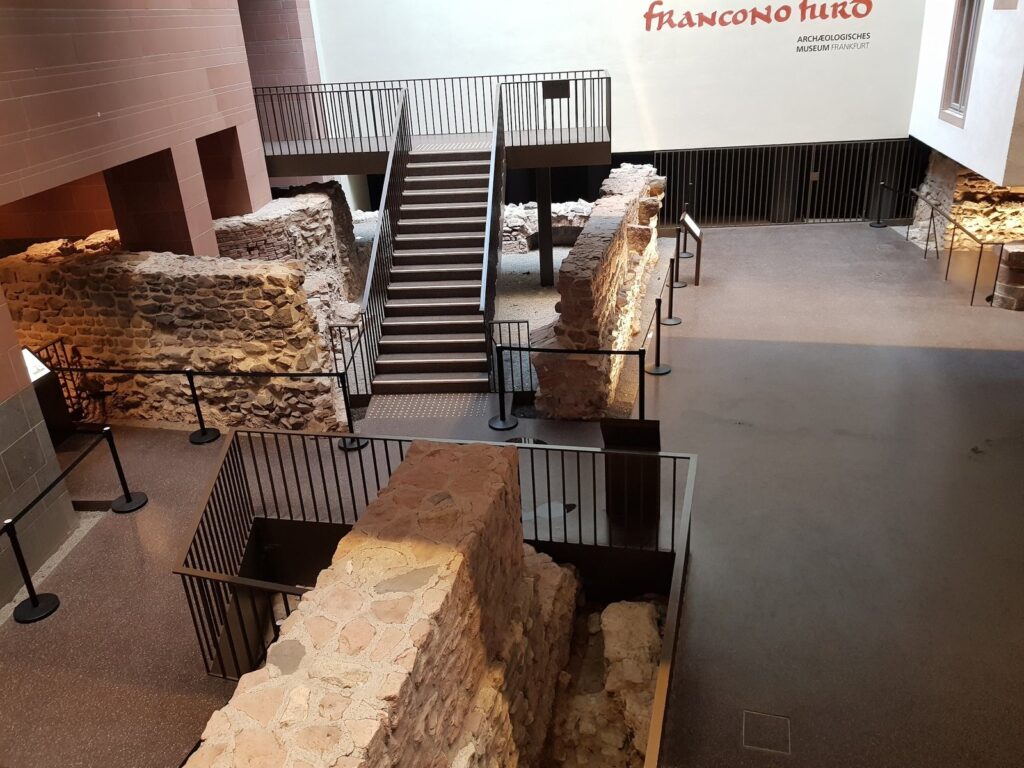 Muros de pedra e escada de visitação da Kaiserpfalz franconofurd, com a placa do Archäologisches Museum Frankfurt