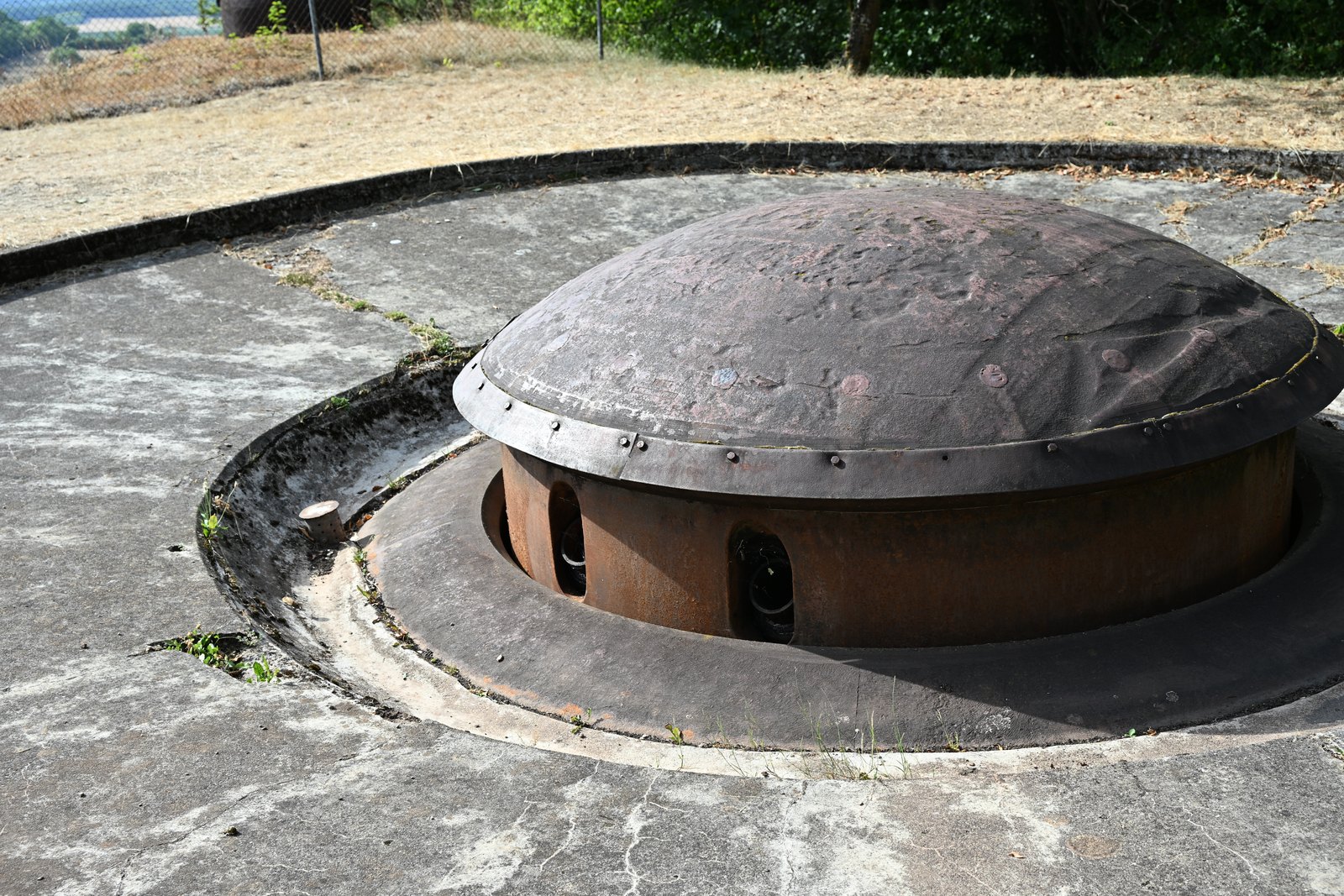Detalhe da cúpula de aço enferrujado da torre retrátil, com o aro rebitado e as aberturas dos canos
