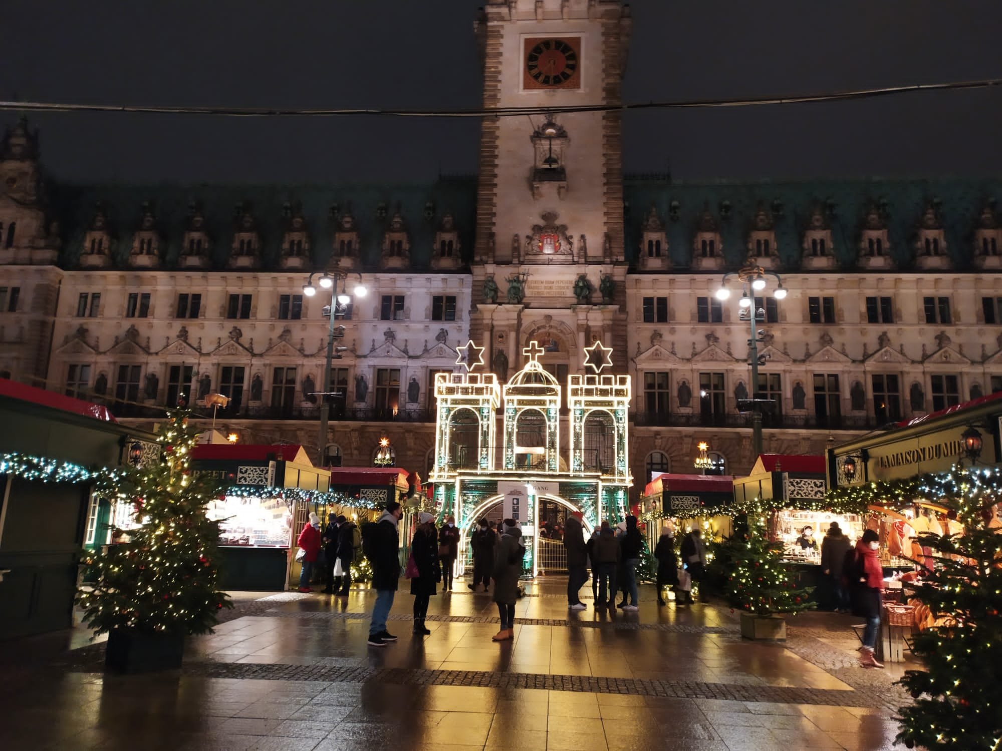 Mercado de Navidad en la Rathausmarkt de Hamburgo, con puestos iluminados y la fachada del ayuntamiento de noche