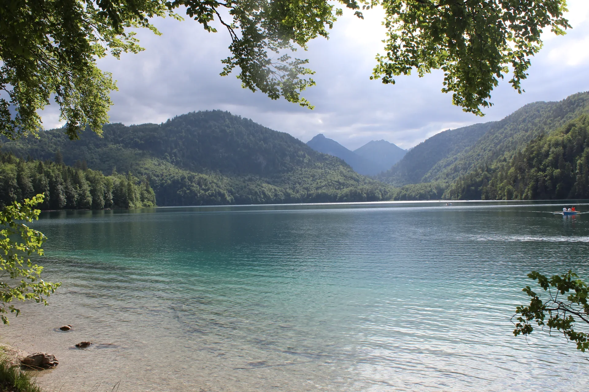 Lago cercado de montanhas e árvores na região de Schwangau, fotografado pela Viagem Alemanha