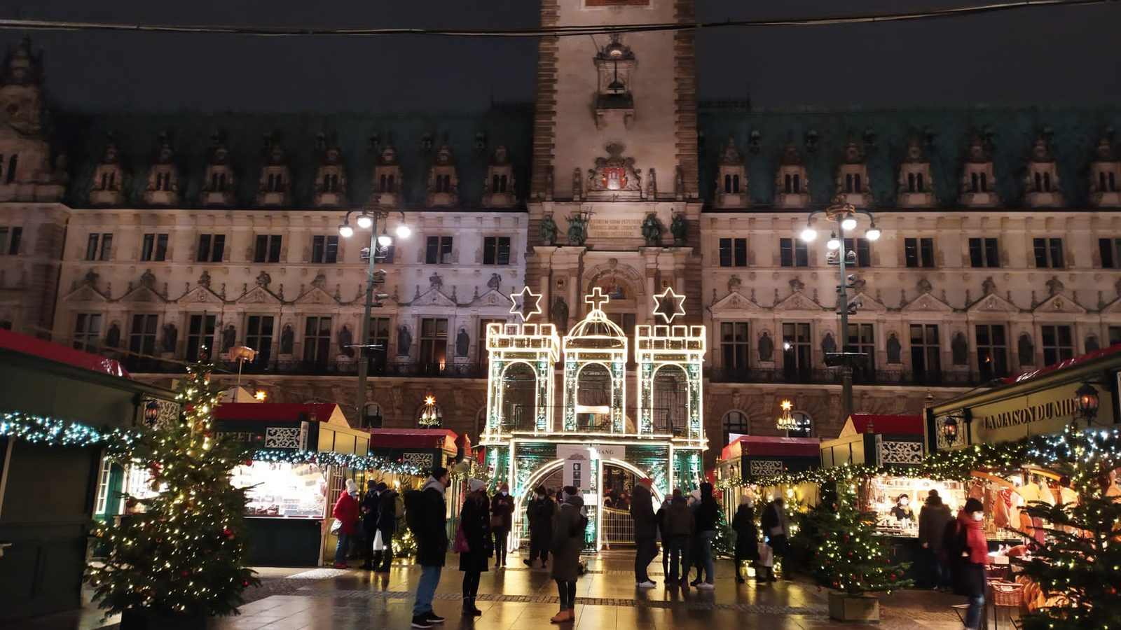 Mercado de Natal no Rathausmarkt de Hamburgo à noite, com o portal iluminado diante da prefeitura
