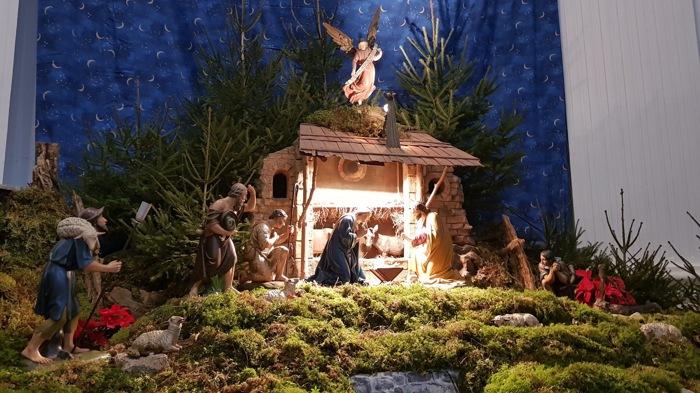 Presépio tradicional montado em uma igreja alemã, com musgo, pinheiros e figuras de madeira