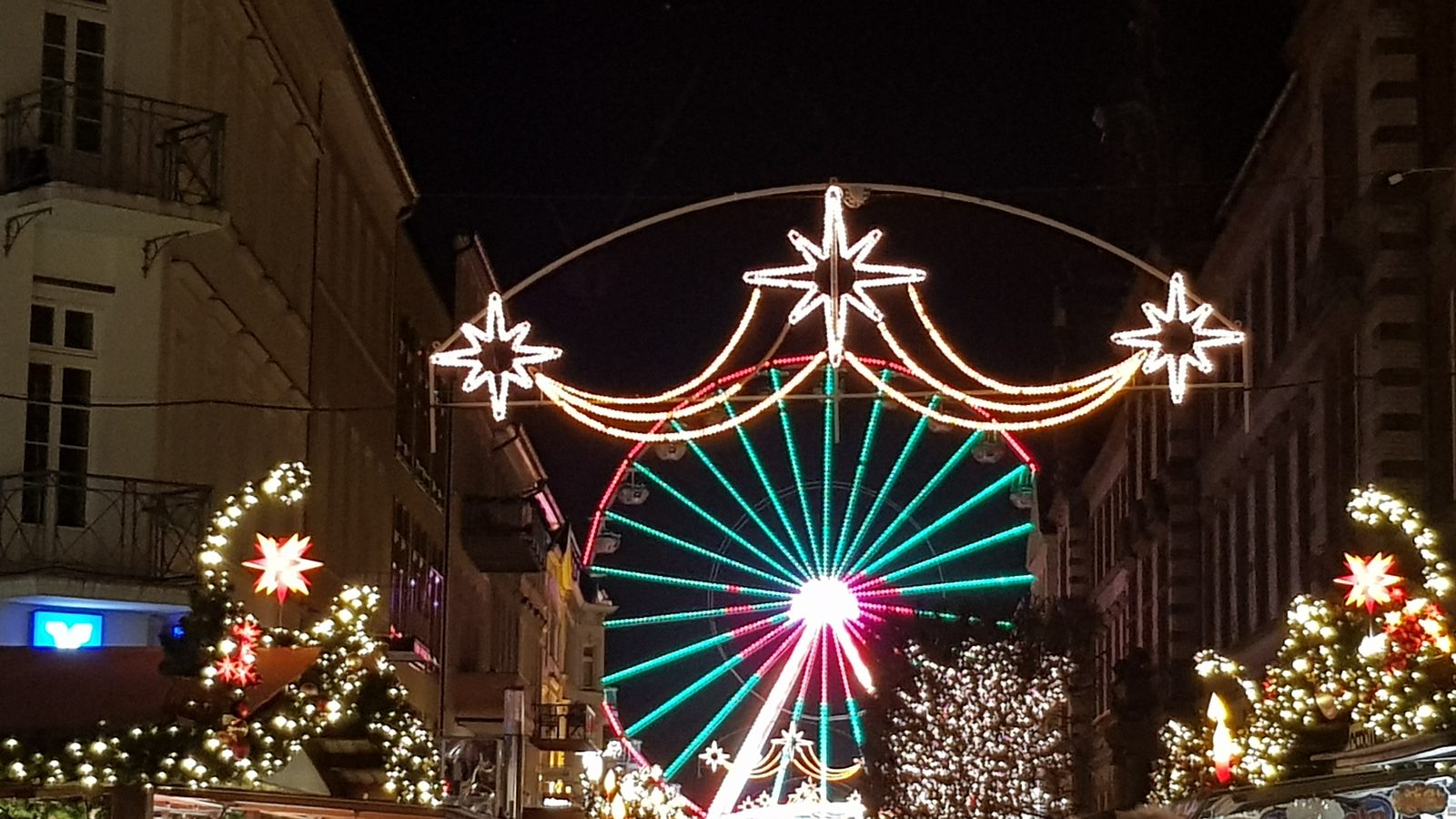 Roda-gigante e arcos de estrelas iluminados no mercado de Natal de Schwerin
