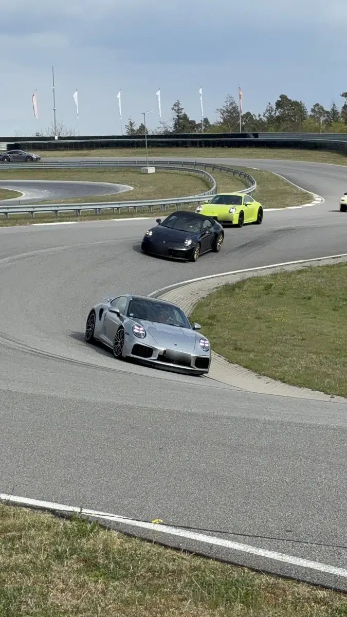 Carros Porsche percorrem uma pista em sequência