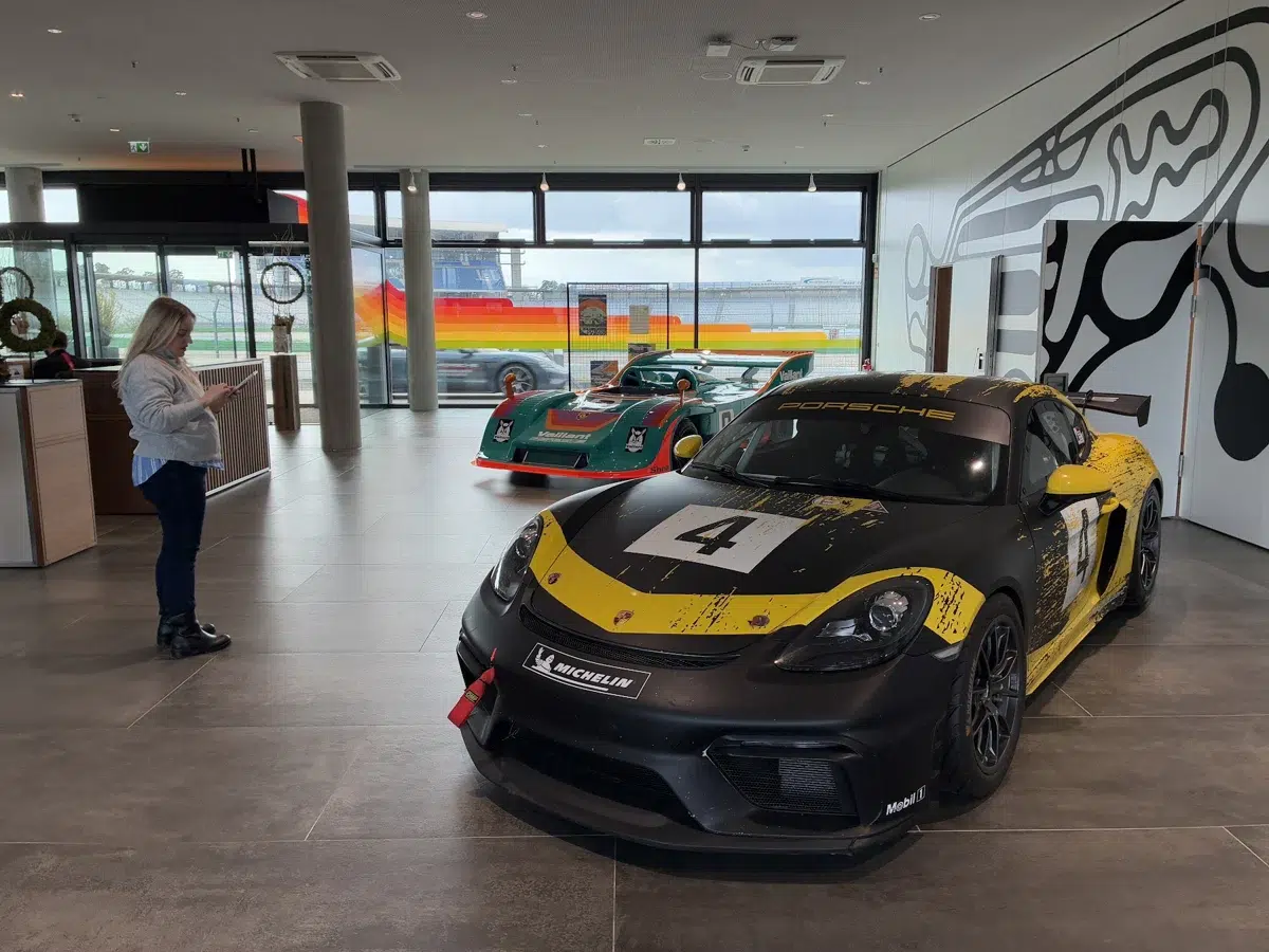 Rafaella observa carros de competição Porsche em exposição