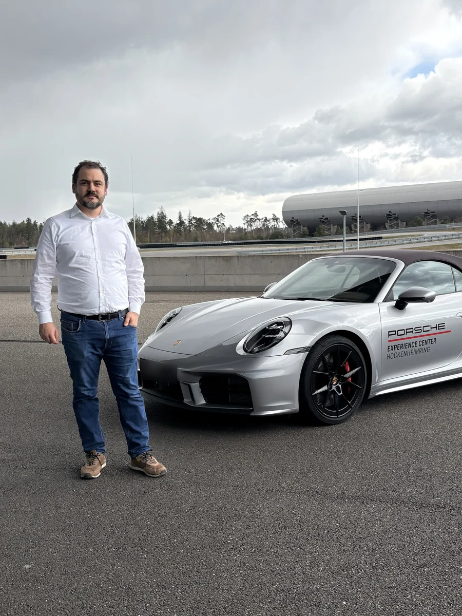 Raphael ao lado de um Porsche no Porsche Experience Center Hockenheimring