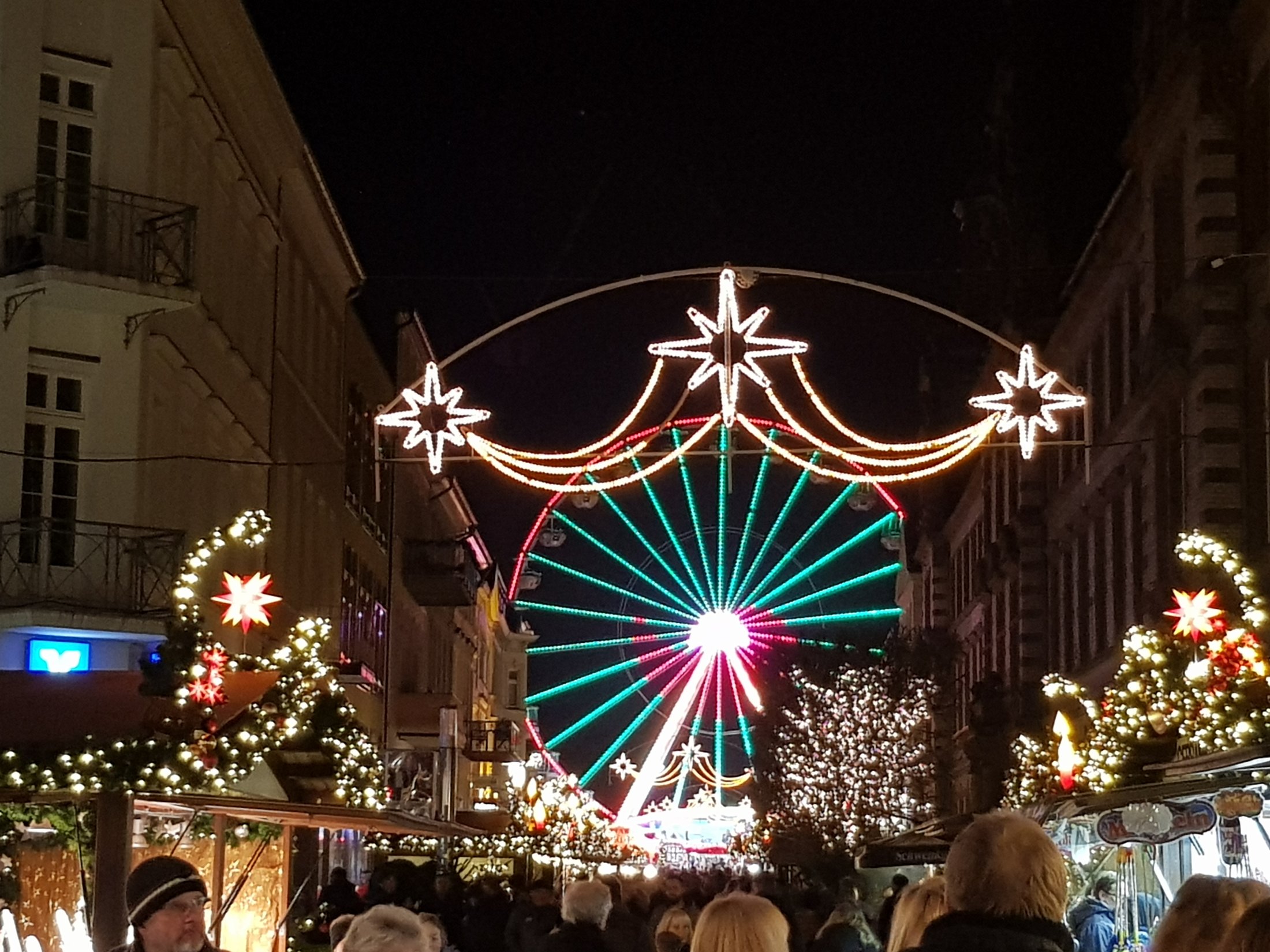 Noria iluminada y arco de estrellas de luz sobre la calle del mercado de Navidad de Schwerin