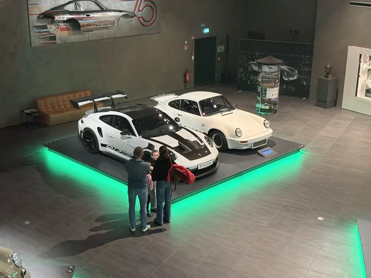 Visitantes diante de carros Porsche em uma exposição