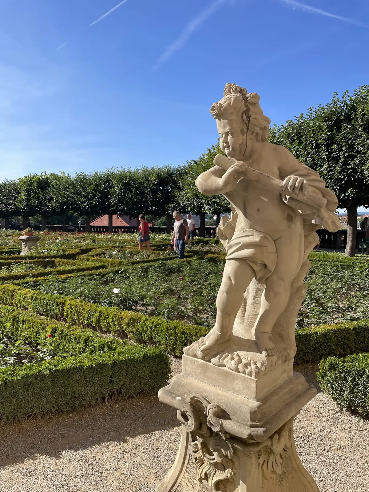 Escultura de pedra entre rosas no jardim da Neue Residenz