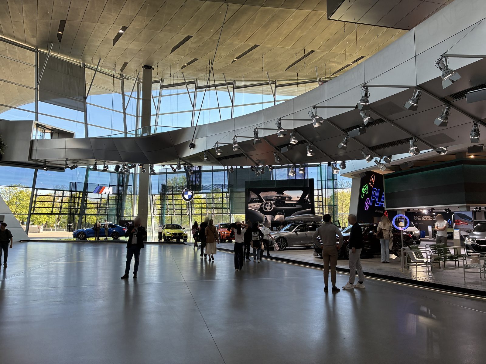 Salão principal do BMW Welt em Munique, com a cobertura ondulada e carros em exposição
