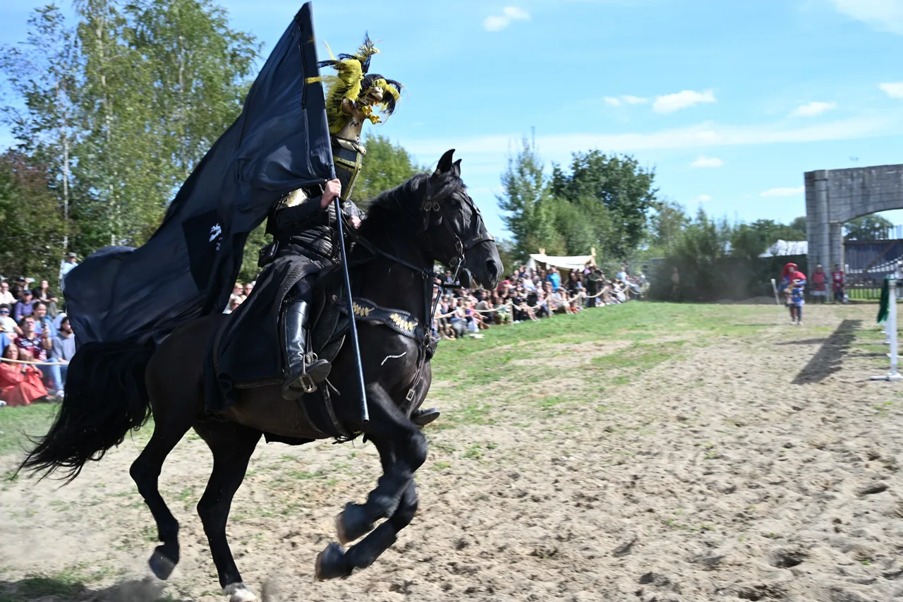 Cavaleiro a cavalo com estandarte durante uma apresentação medieval