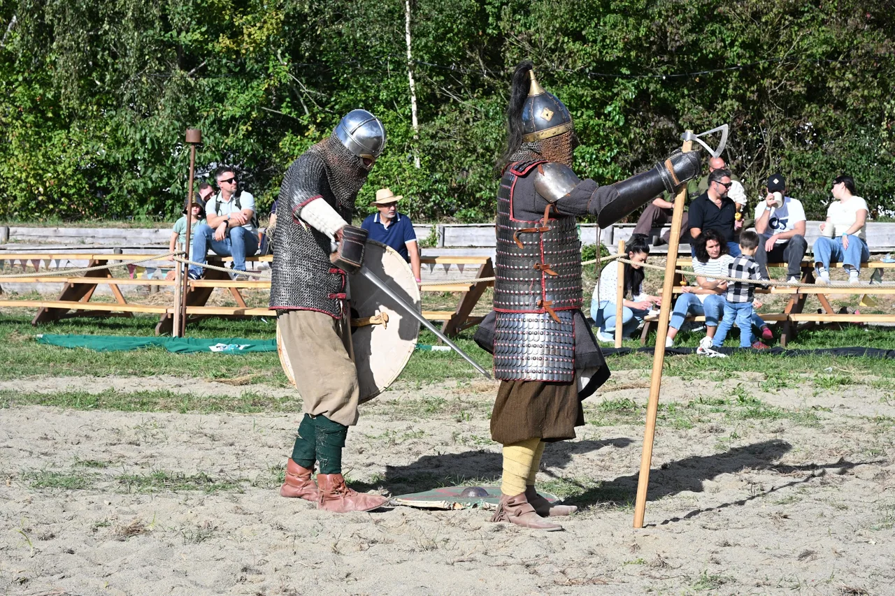 Participantes com armaduras e escudos em uma demonstração de combate medieval