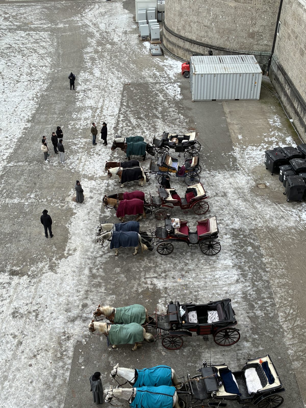 Carruagens com cavalos cobertos por mantas coloridas enfileiradas na Domplatz coberta de neve, vistas do alto