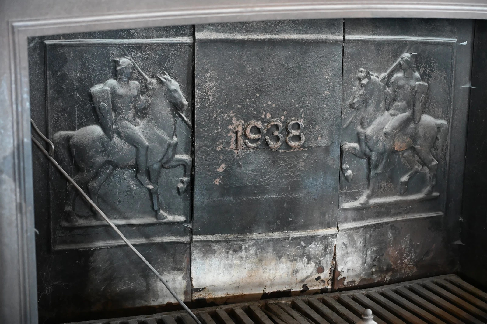 Painel metálico da lareira com a inscrição 1938 e figuras em relevo