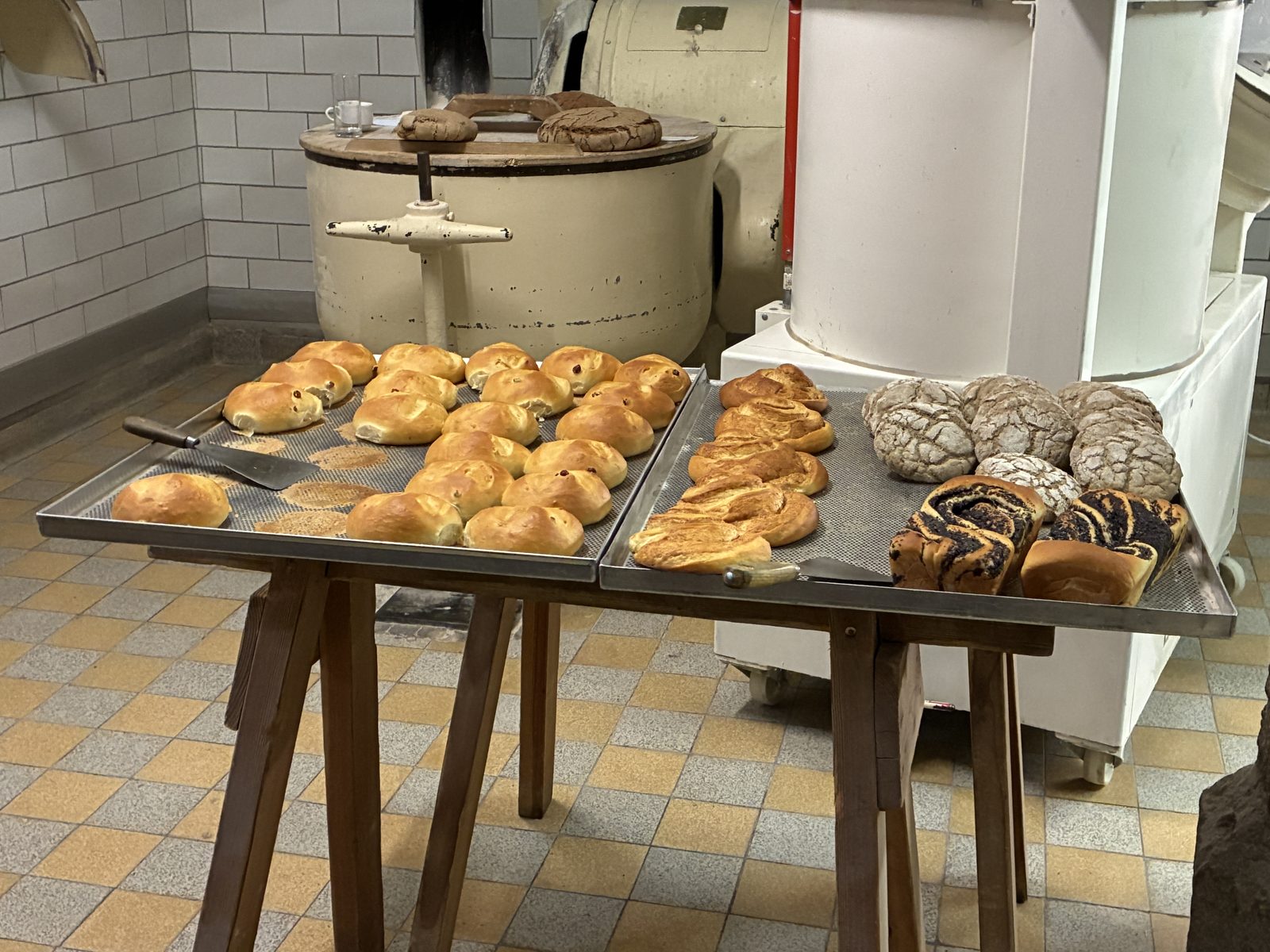 Bandejas de pães e roscas recém-assados sobre uma mesa de madeira na padaria da abadia de St. Peter