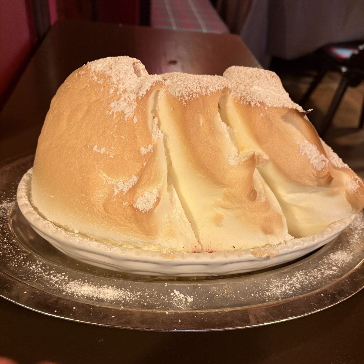 Salzburger Nockerl, suflê doce dourado com picos polvilhados de açúcar, servido numa travessa no restaurante St. Peter Stiftskulinarium