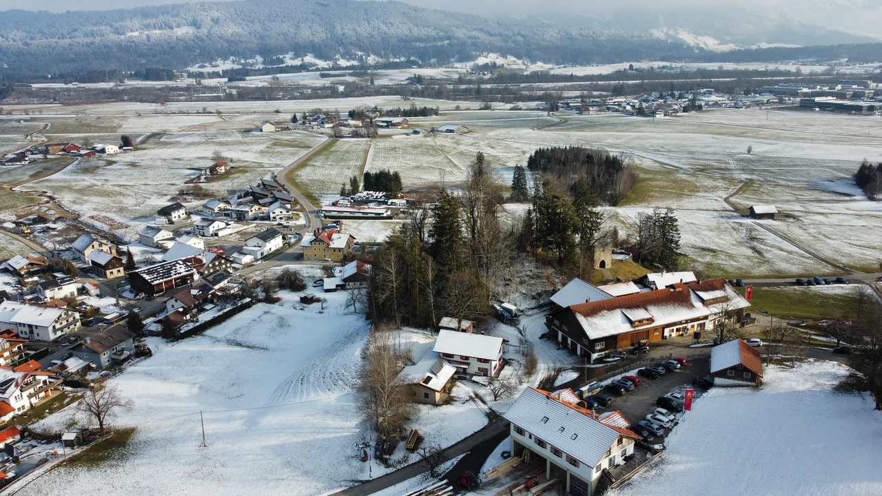 Casas, uma igreja e campos parcialmente cobertos de neve na região de Immenstadt