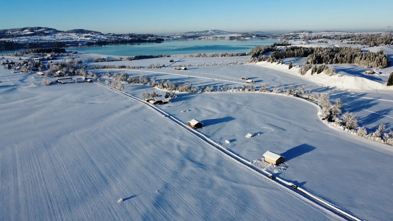 Campos, caminhos e uma igreja junto a uma paisagem coberta de neve em Schwangau