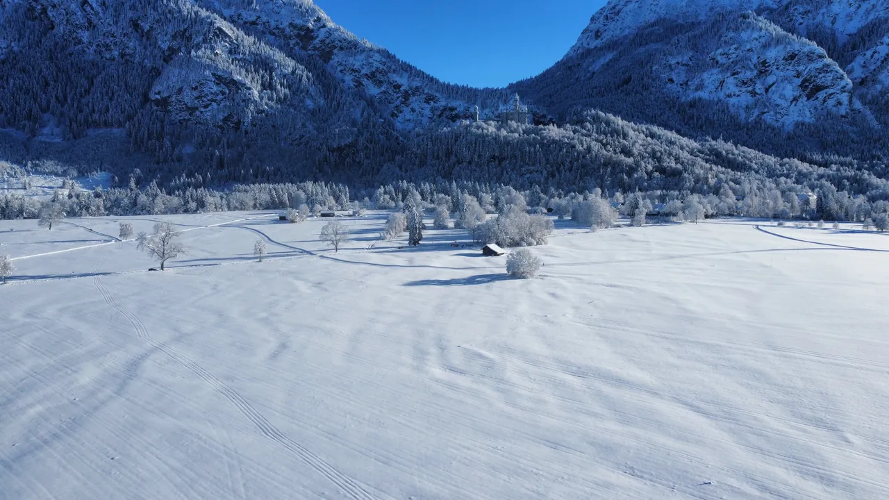 Campos cobertos de neve e picos dos Alpes vistos do alto em Schwangau