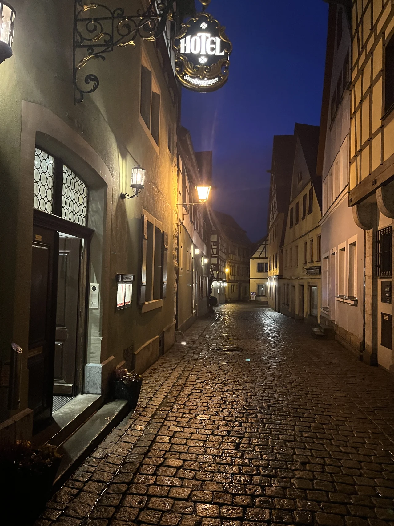 Rua de pedras em Rothenburg iluminada por lanternas ao anoitecer, entre fachadas históricas